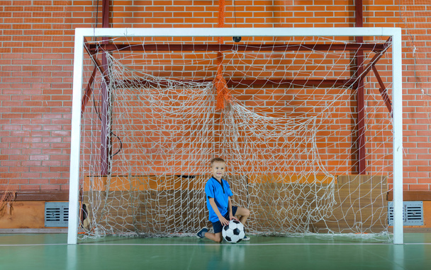 Νεαρό αγόρι παίζει τερματοφύλακα κρατώντας μια μπάλα ποδοσφαίρου - Φωτογραφία, εικόνα
