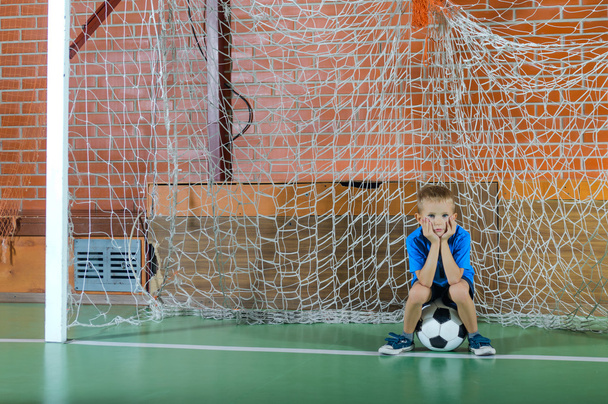 Молодий хлопчик грає воротаря, який тримає футбольний м'яч
 - Фото, зображення