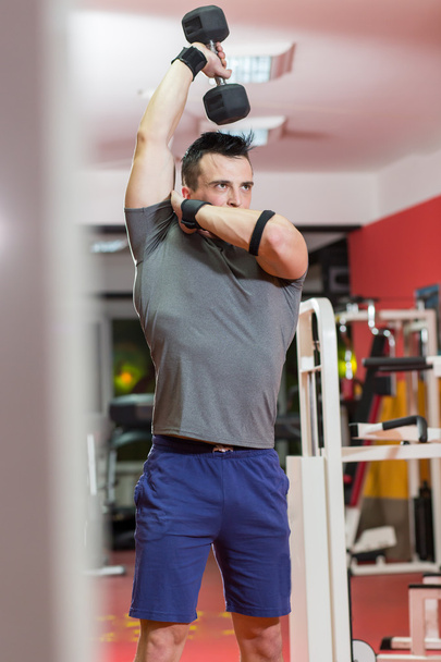 muscular man lifting dumbbell at the gym - Fotoğraf, Görsel