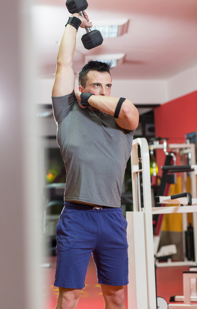 muscular man lifting dumbbell at the gym - Fotó, kép