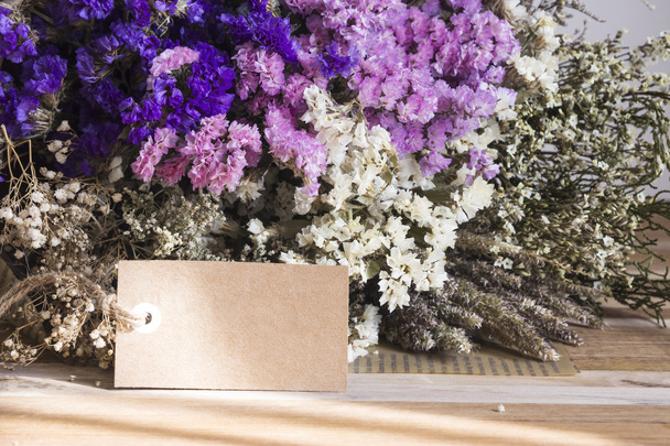 木製テーブルの上タグの空白の紙とドライフラワーの花束 - 写真・画像