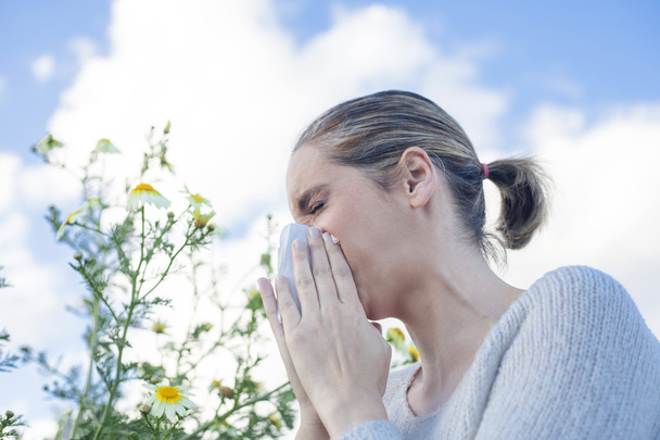 Mujer estornudando en un prado de flores de margarita
 - Foto, Imagen