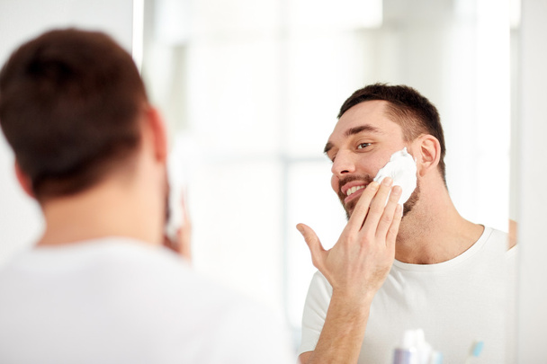 happy man applying shaving foam at bathroom mirror - Photo, image