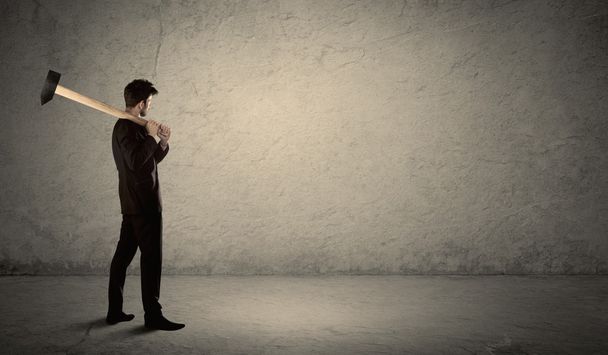 Επιχειρηματίας στέκεται μπροστά από ένα grungy τοίχο με ένα σφυρί - Φωτογραφία, εικόνα