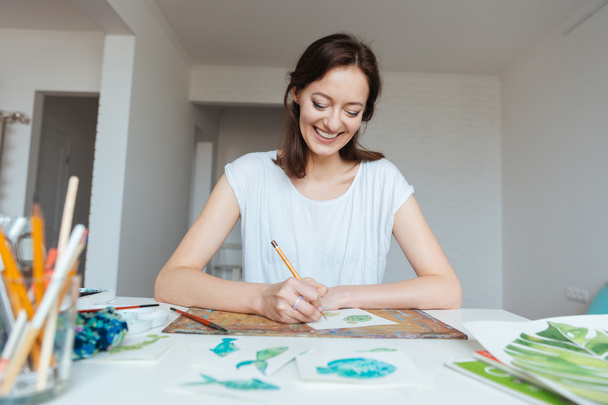 Cheerful female painter making sketches in workshop  - Фото, зображення