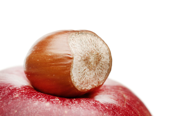 Brown hazelnut on red apple top, close-up. - Photo, Image