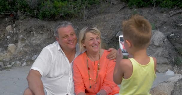 Niño tomando fotos de abuelos con teléfono celular
 - Metraje, vídeo