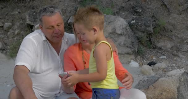 Jongen en grootouders kijken naar foto's op smartphone - Video