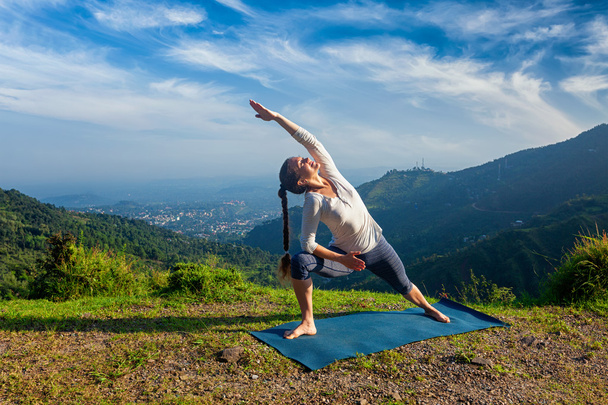Femme pratique le yoga asana Utthita Parsvakonasana en plein air - Photo, image