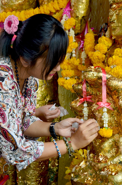 Tailandês mulher deslizar capa anjo estátua com folha de ouro em Phra Kal Sh
 - Foto, Imagem