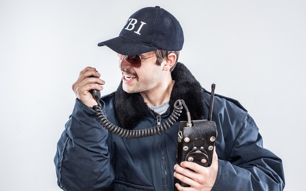 boos fbi-agent in situaiton met blauwe jas, retro radio en GLB - Foto, afbeelding
