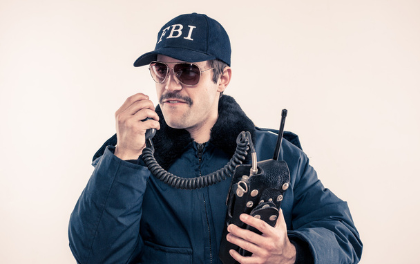 Angry FBI agent in riot jacket about to swear over vintage radio - Photo, Image