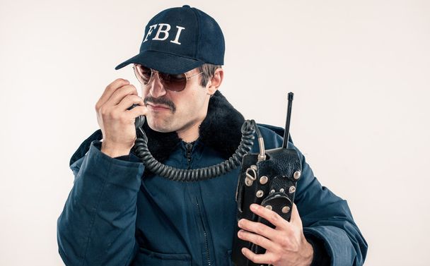 jonge witte fbi officier in blauwe jas praten op vintage radio - Foto, afbeelding