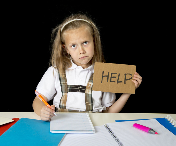 втомлена мила молодша школярка зі світлим волоссям, що сидить у стресі, працюючи над домашнім завданням, виглядає нудно
 - Фото, зображення