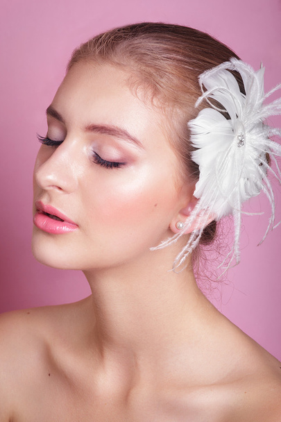 Portrait of beautiful bride .Portrait of a beautiful woman in the image of the bride with decoration feather in her hair. Picture taken in the studio on a pink background. - Фото, зображення