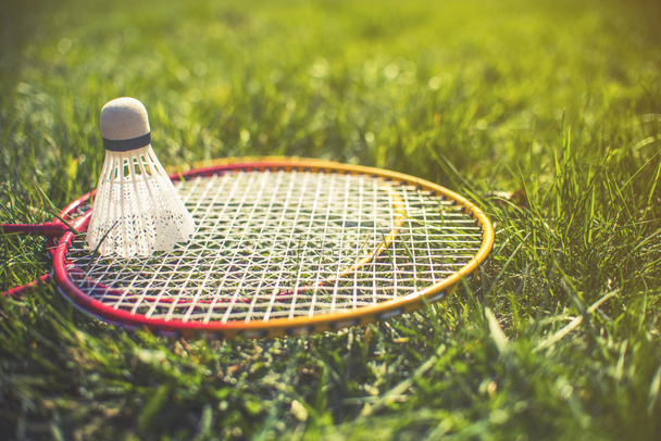 Shuttlecock and badminton racket on green grass - Foto, afbeelding