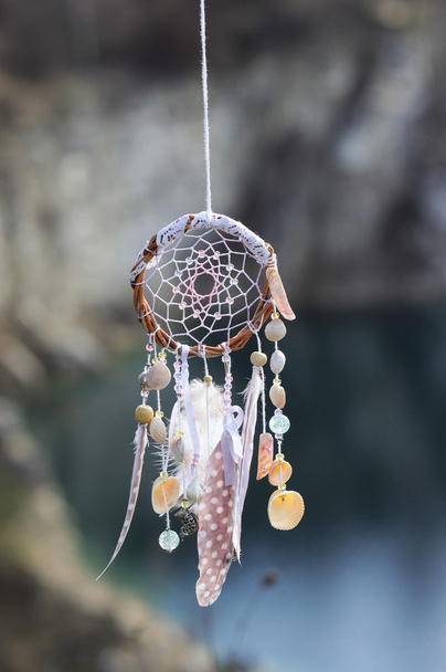 Handmade native american dream catcher on background of rocks and lake - Photo, Image