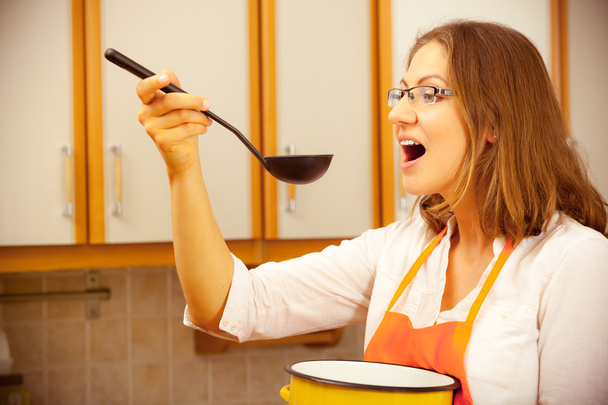 Woman with ladle and pot in kitchen - Zdjęcie, obraz