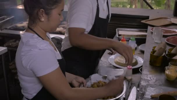 Twee restaurant koks bereiden voedsel bij een buiten balie naast elkaar - Video