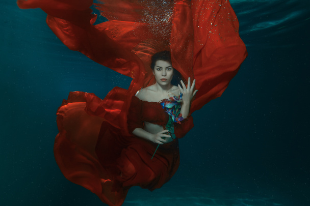 kobieta w czerwonej sukience pod wodą. - Zdjęcie, obraz