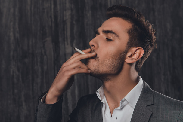 Close up portrait of pretty businessman smoking a sigarette - Foto, afbeelding