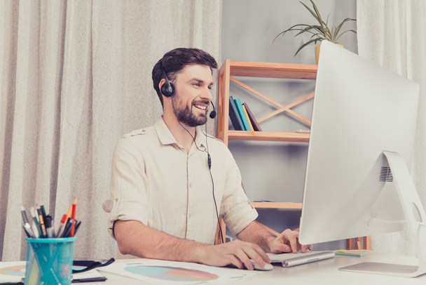 Happy cheerful young worker of call center in head-phones - 写真・画像
