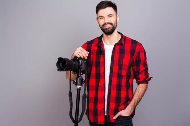 Portrait of handsome young cameraman standing in studio with cam - 写真・画像