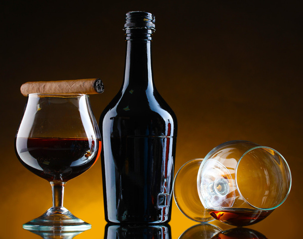 Bottle and glasss of brandy and cigar on brown background - Photo, Image
