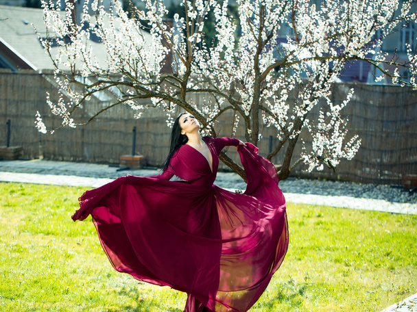 Girl in red dress near blossom - Foto, immagini
