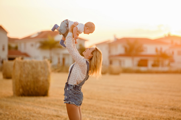 Slender beautiful blonde mom in jeans suit baby throws up in the - Foto, Imagen