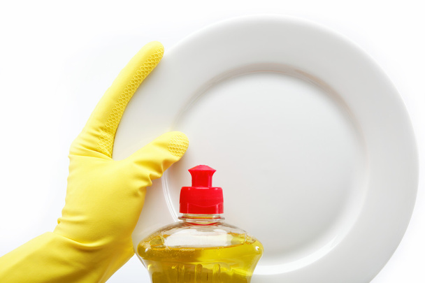 Hand in rubber glove with a plate and a bottle of detergent on a - Photo, Image