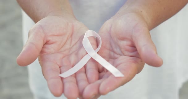 Otwarte dłonie trzymając wstążkę świadomości raka piersi - Materiał filmowy, wideo