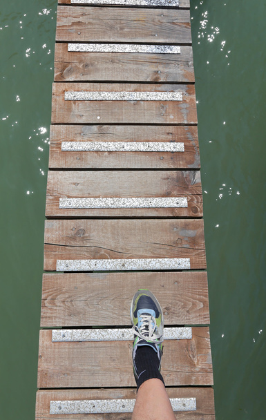 pé com o sapato esporte acima da passarela no meio do
  - Foto, Imagem