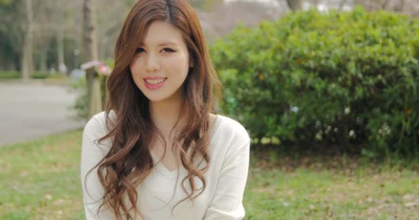 Atraktivní japonská dívka, která nosí bílé úsměvy pro fotoaparát, posuvné shot  - Záběry, video
