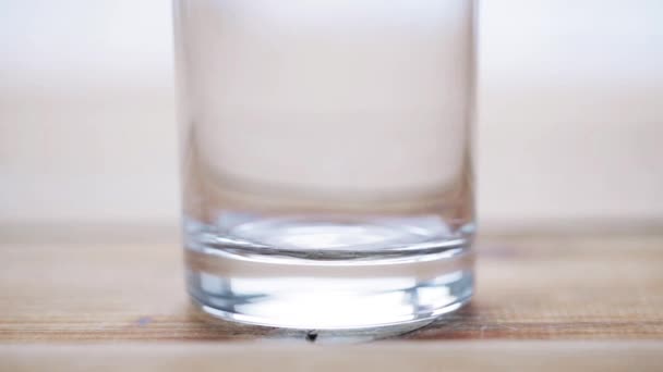 milk pouring into empty glass on wooden table - Filmati, video