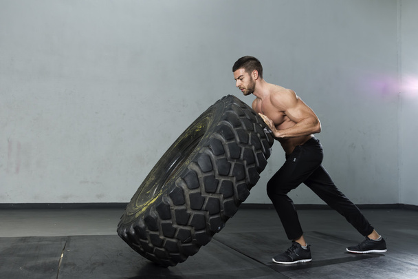 Bodybuilder flipping tire at the gym - Photo, Image