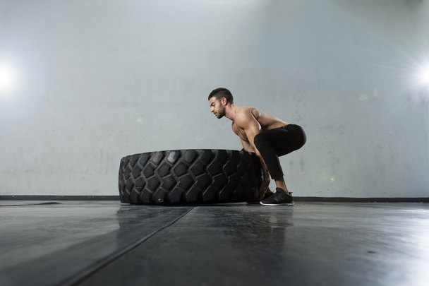 Bodybuilder flipping tire at the gym - Foto, afbeelding