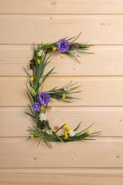 The letter made up of grass and flowers on a background of wooden planks - Fotografie, Obrázek