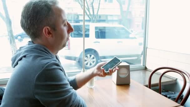 Muž textových zpráv a prohlížení s mobily v kavárně - Záběry, video
