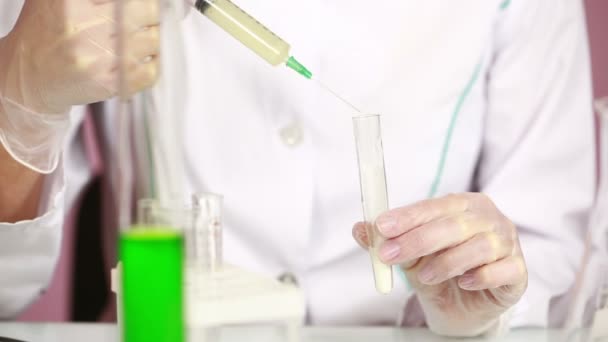 Química femenina comparando tubos de ensayo con productos químicos. gafas protectoras
 - Metraje, vídeo