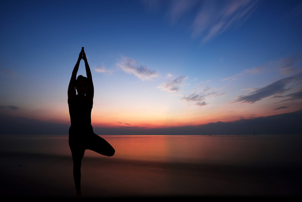 Nainen harrastaa joogaa auringonlaskun aikaan - Valokuva, kuva