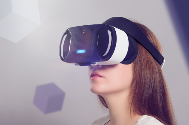 Woman in VR headset looking up at the objects in virtual reality - Photo, Image