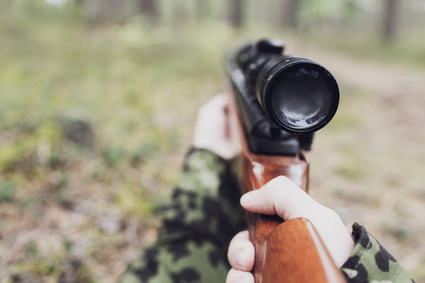 close up of soldier or hunter with gun in forest - Photo, Image
