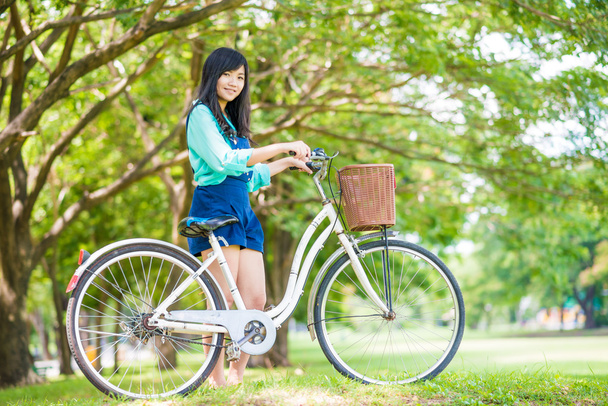 Aasialainen söpö nainen polkupyörällä puutarhassa, julkinen puisto
. - Valokuva, kuva