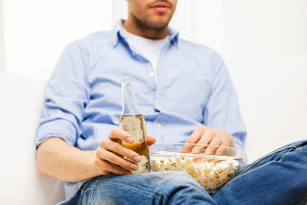 close up of man with popcorn and beer at home - Foto, immagini