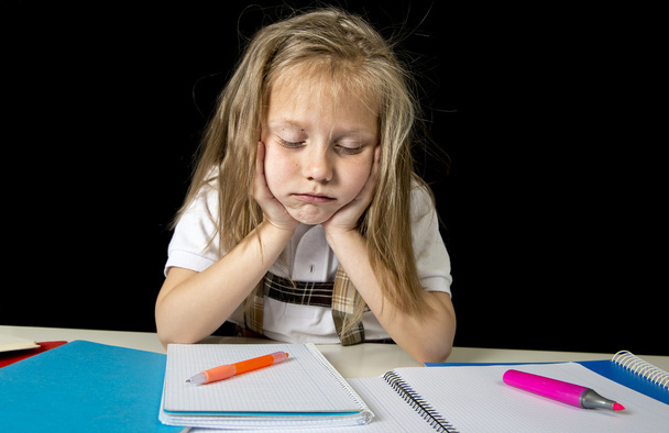 сумна втомлена мила блондинка молодша школярка в стресі, що працює над домашнім завданням нудно перевантажена
  - Фото, зображення