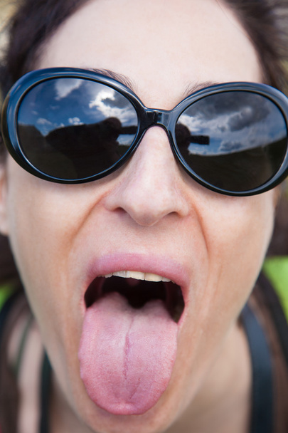 femelle avec des lunettes de soleil sortant de sa langue
 - Photo, image