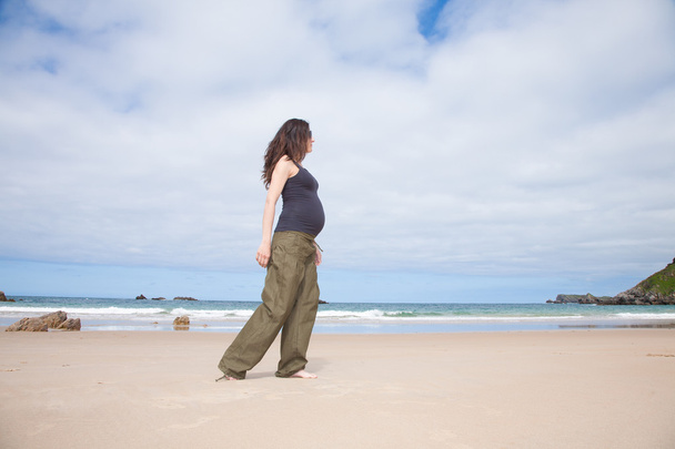 grey shirt pregnant walking next to ocean - Photo, Image