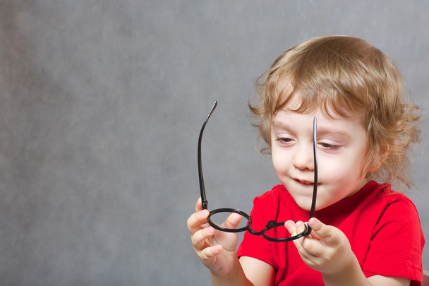 Un ragazzo di 3 anni si mette gli occhiali
 - Foto, immagini