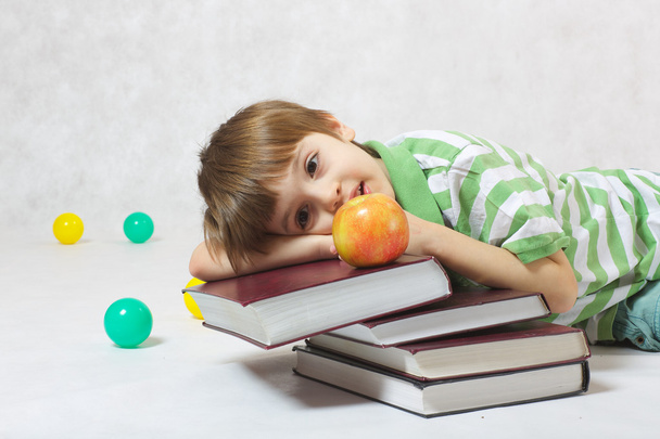 Een jongen met een appel en een stapel boeken - Foto, afbeelding